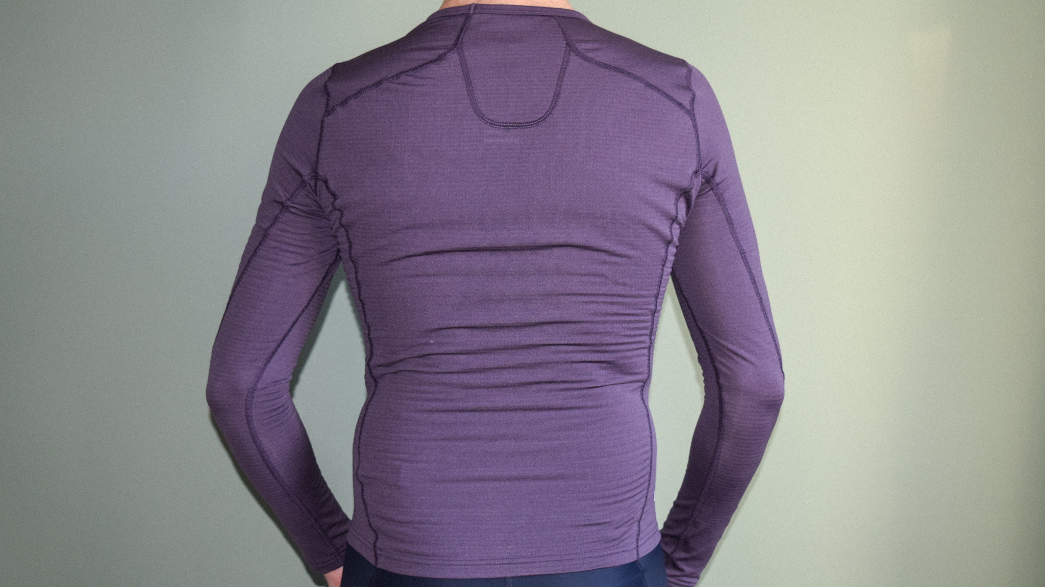 Une couche de base violette Maap Thermal LS vue de derrière portée par un homme.  Les coutures traversent les épaules et autour de la nuque