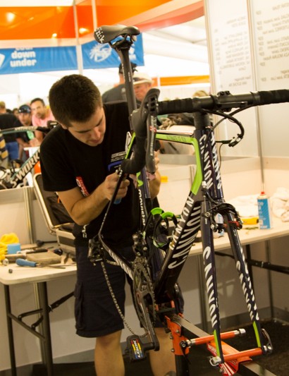 Les baies mécaniques de Tour Down Under ressemblent à de petites cabines de bureau.  Tous les mécaniciens travaillent les uns à côté des autres sous les yeux du public