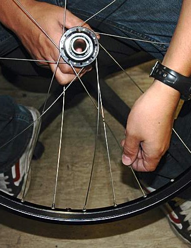 Complétez ce côté de la roue en insérant un rayon à travers la bride à deux trous dans le sens inverse des aiguilles d'une montre à partir de celui déjà vers le haut dans le moyeu.