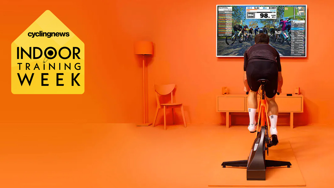 Un homme utilisant Zwift sur un turbo trainer, dans une pièce entièrement orange, avec le badge Le Dérailleur Indoor Training Week superposé