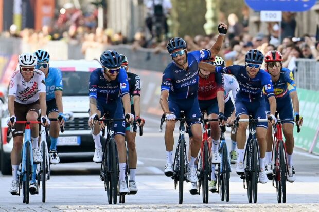 Thibaut Pinot waves to the crowd as he crosses the finish line with his Groupama-FDJ teammates on the final race of his career