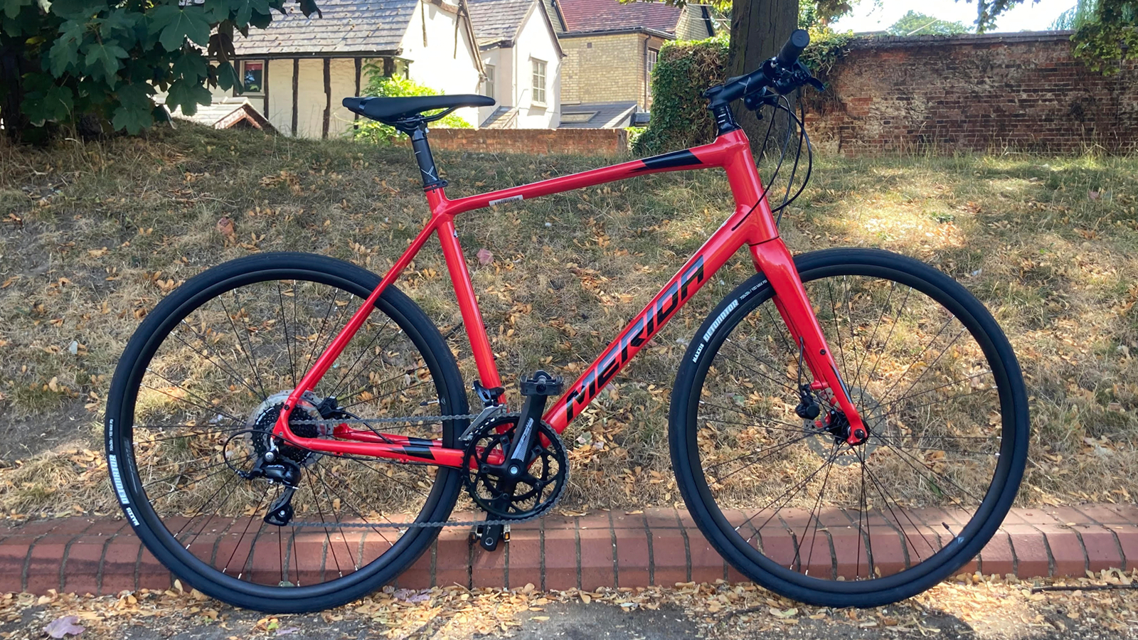 Un vélo hybride Merida se tient devant un banc d'herbe