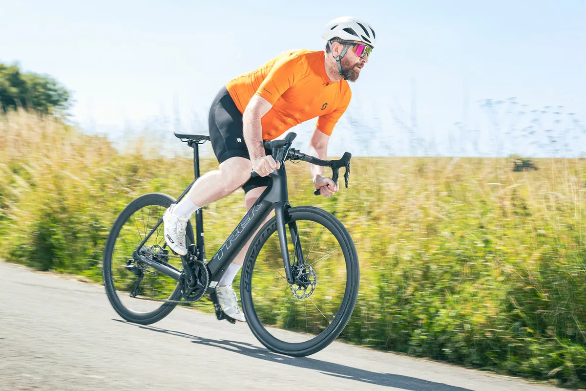 Cycliste masculin en haut orange sur le vélo électrique de route Trek Domane SLR 6