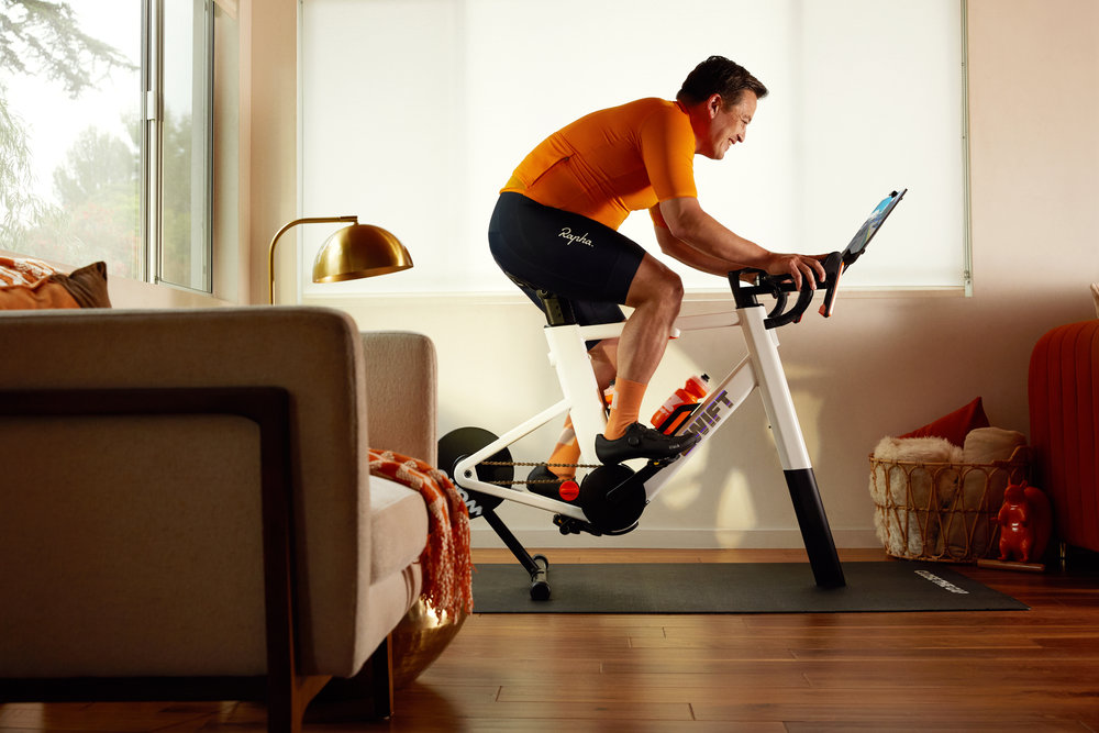 Un homme monte un home trainer intelligent Zwift Ride dans un salon