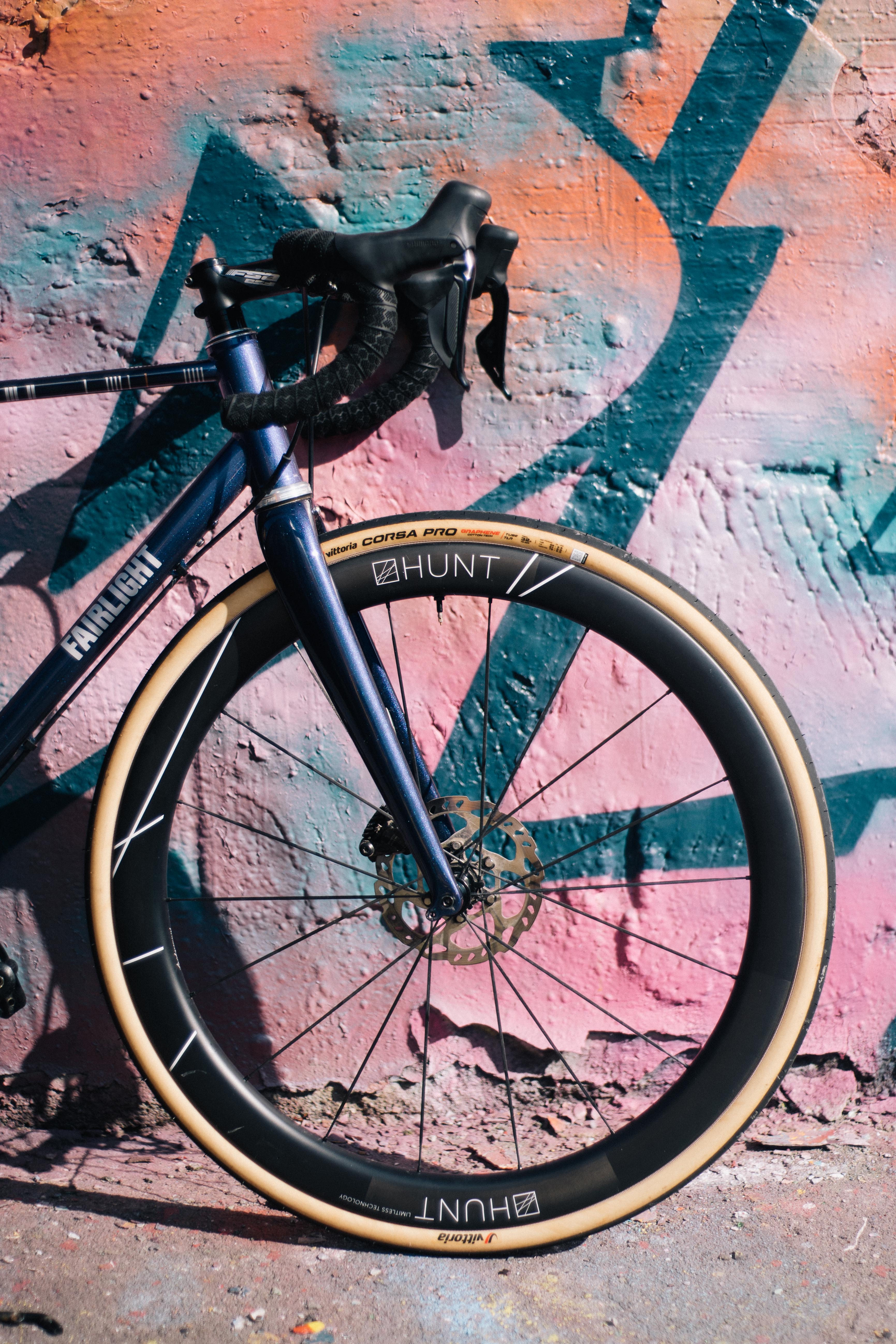 Une vue latérale de l'avant d'un vélo de route bleu sur fond de graffitis.