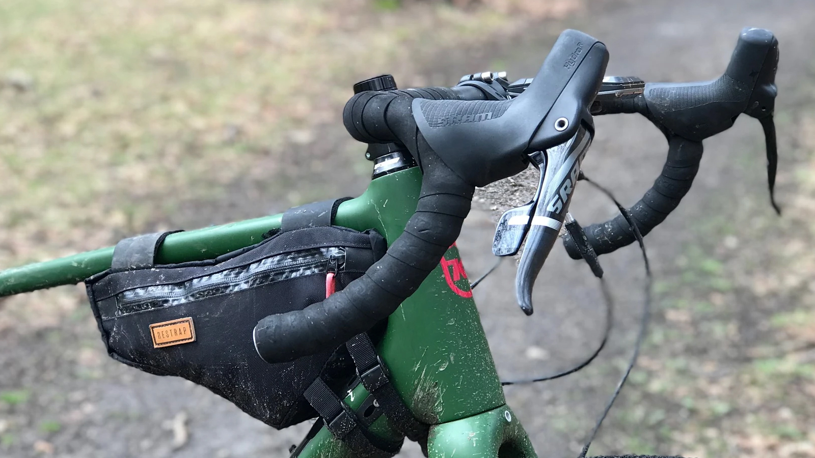 Un vélo de gravel vert avec une sacoche de cadre pour tube supérieur et des barres évasées