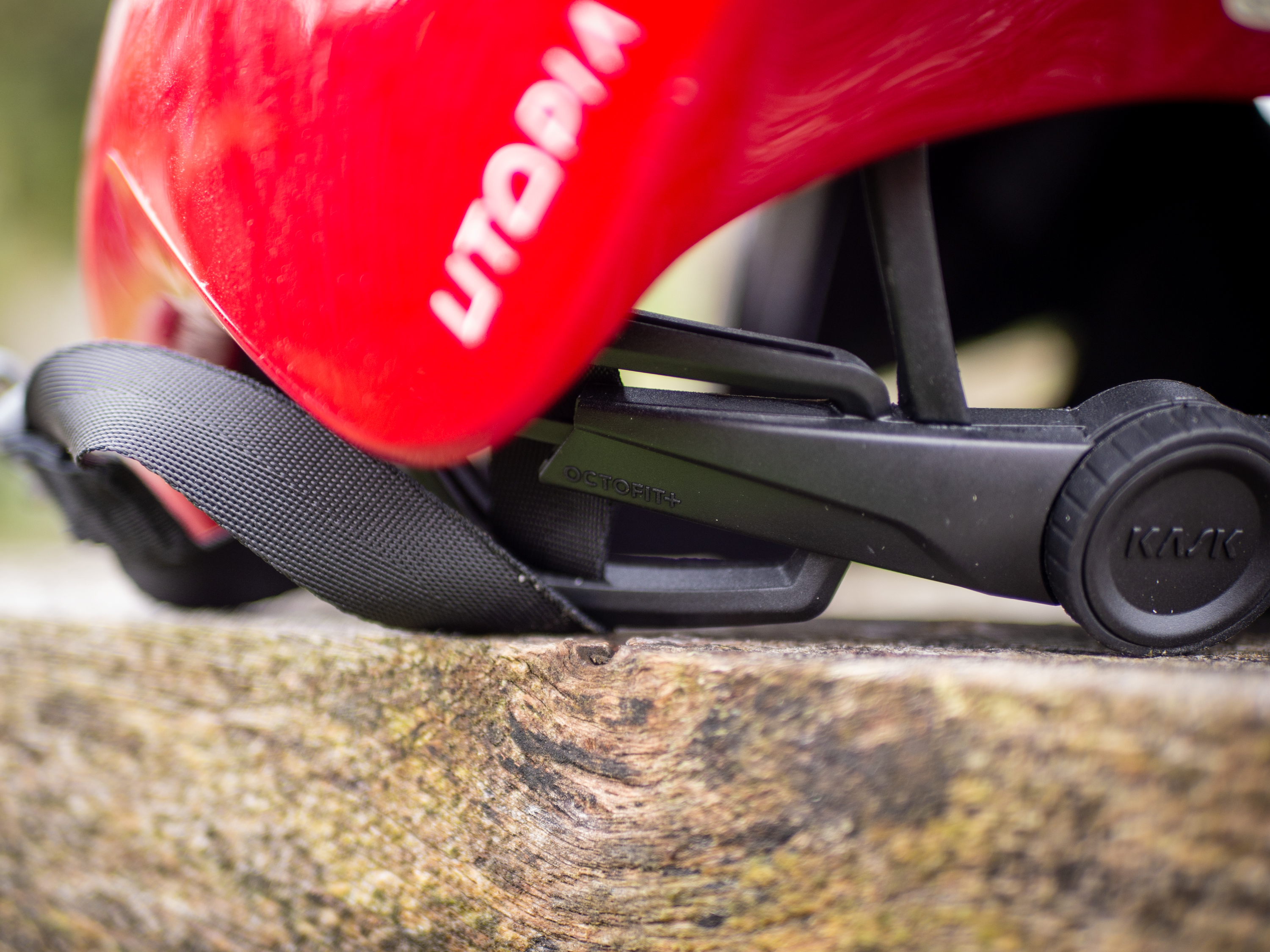 Un casque aérodynamique Kask Utopia Y rouge est posé sur un banc en bois