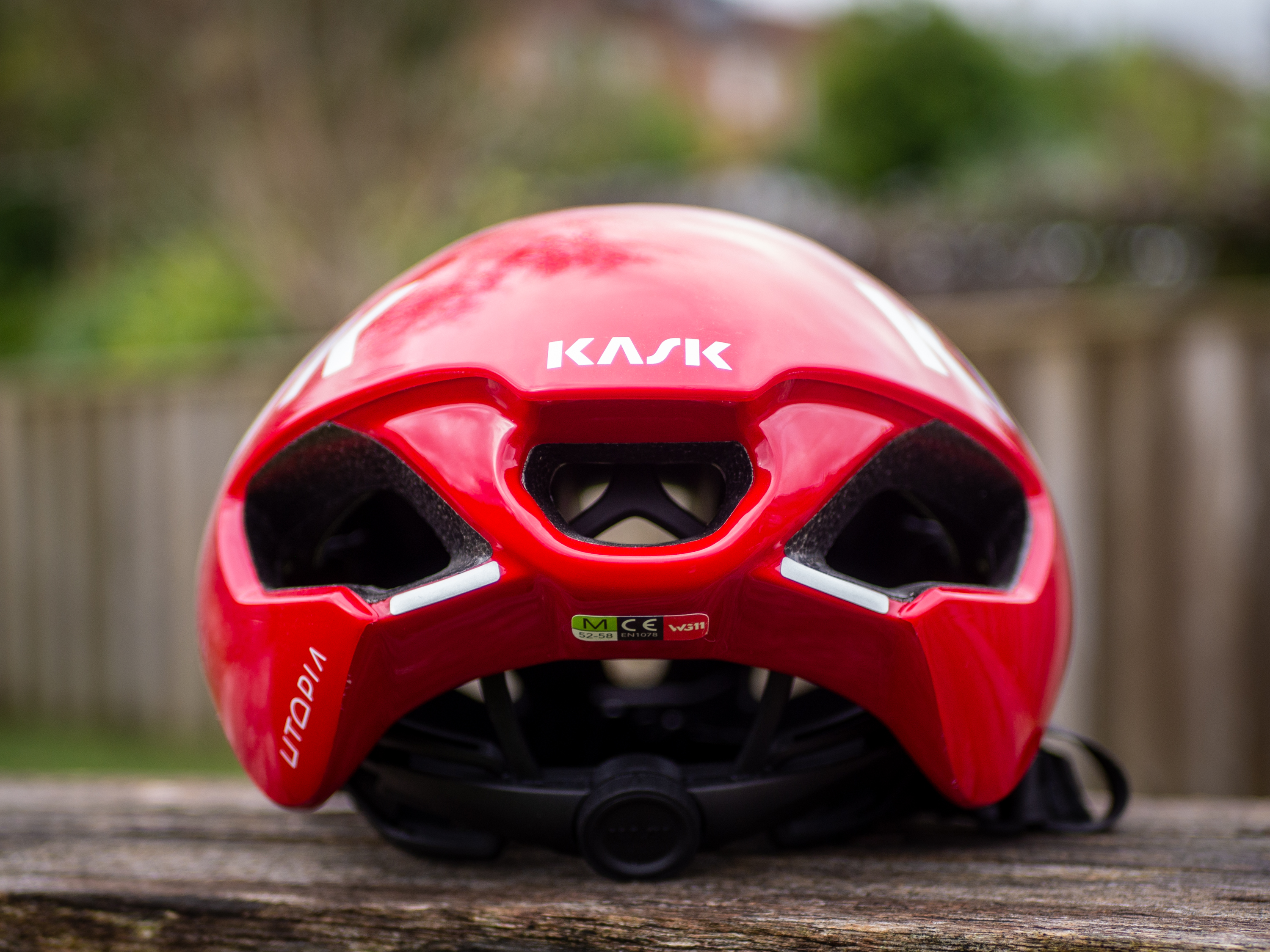 Un casque aérodynamique Kask Utopia Y rouge est posé sur un banc en bois