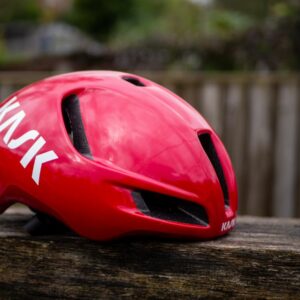 A red Kask Utopia Y aero helmet sits on a wooden bench