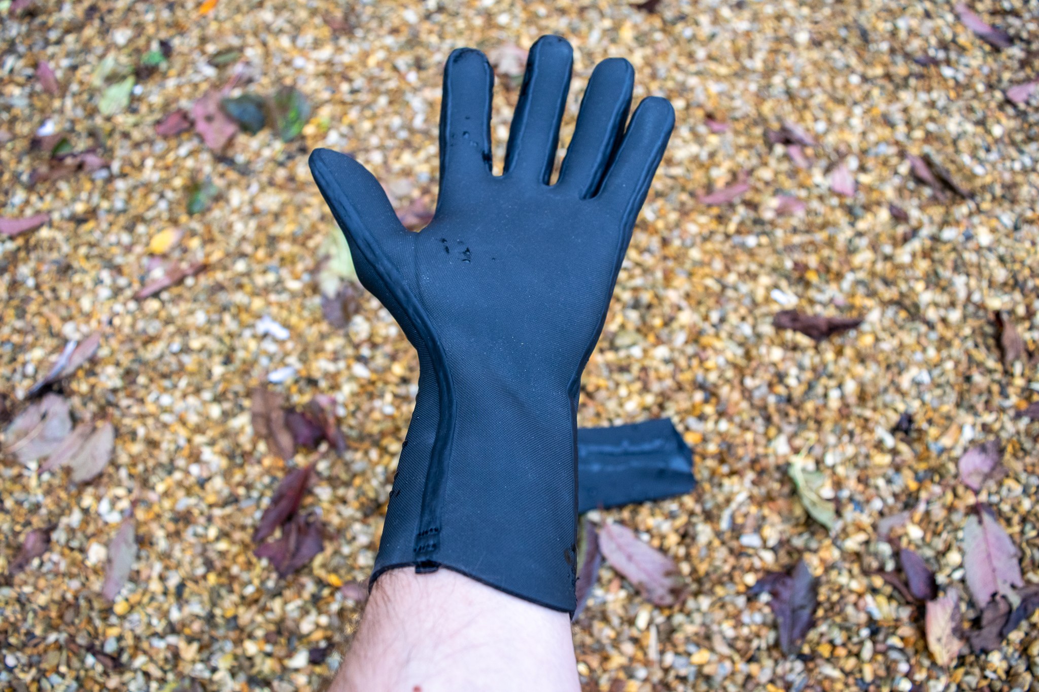 Gants en néoprène Velotoze sur du gravier avec des gouttelettes d'eau dessus