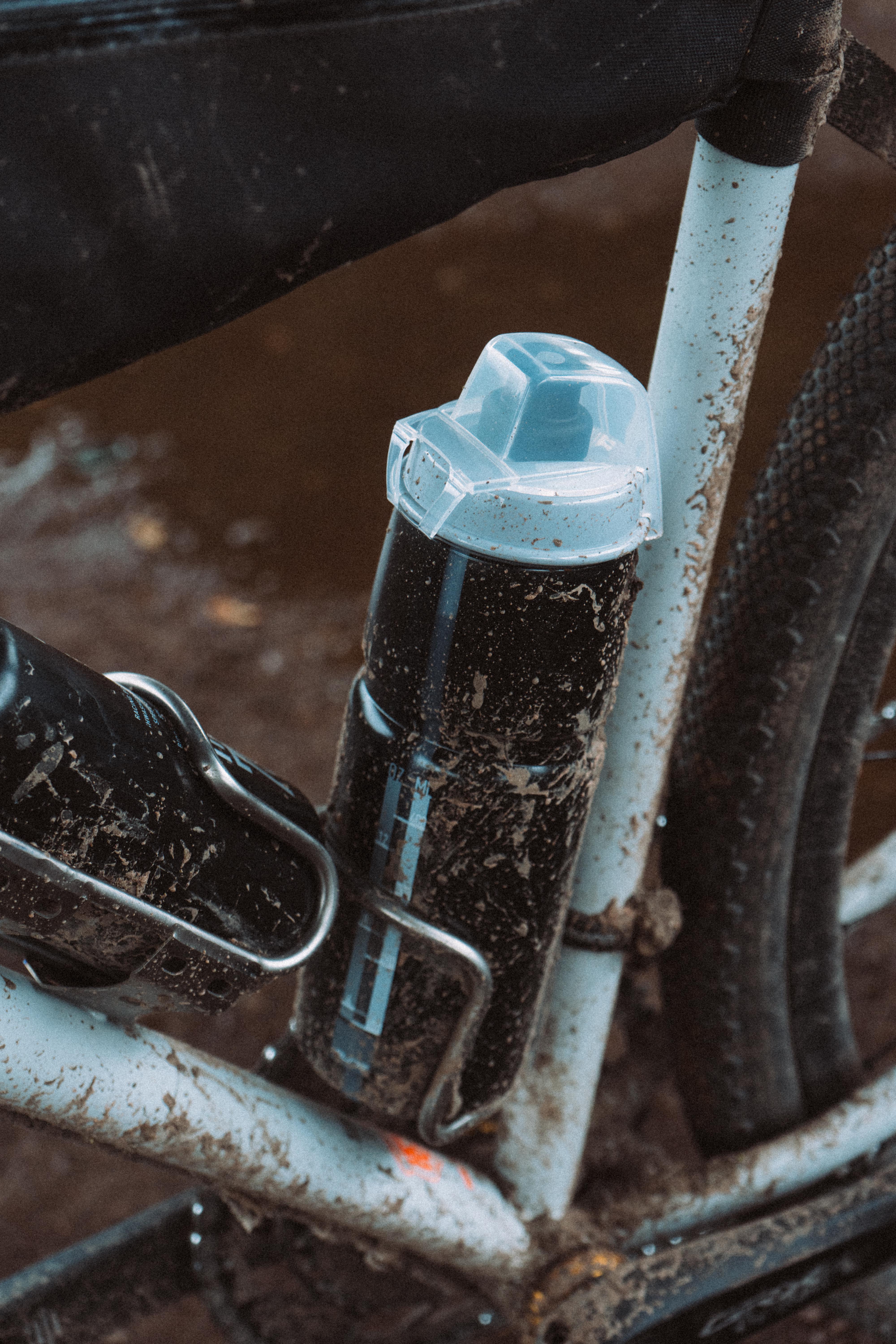 Une bouteille d'eau noire avec un bouchon transparent montée sur un cadre de vélo noir