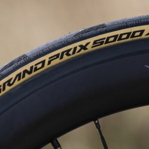 A tan-wall Continental Grand Prix 5000 AS TR tyre mounted to a black carbon rim