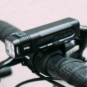 A black bike light mounted on top of a set of handlebars