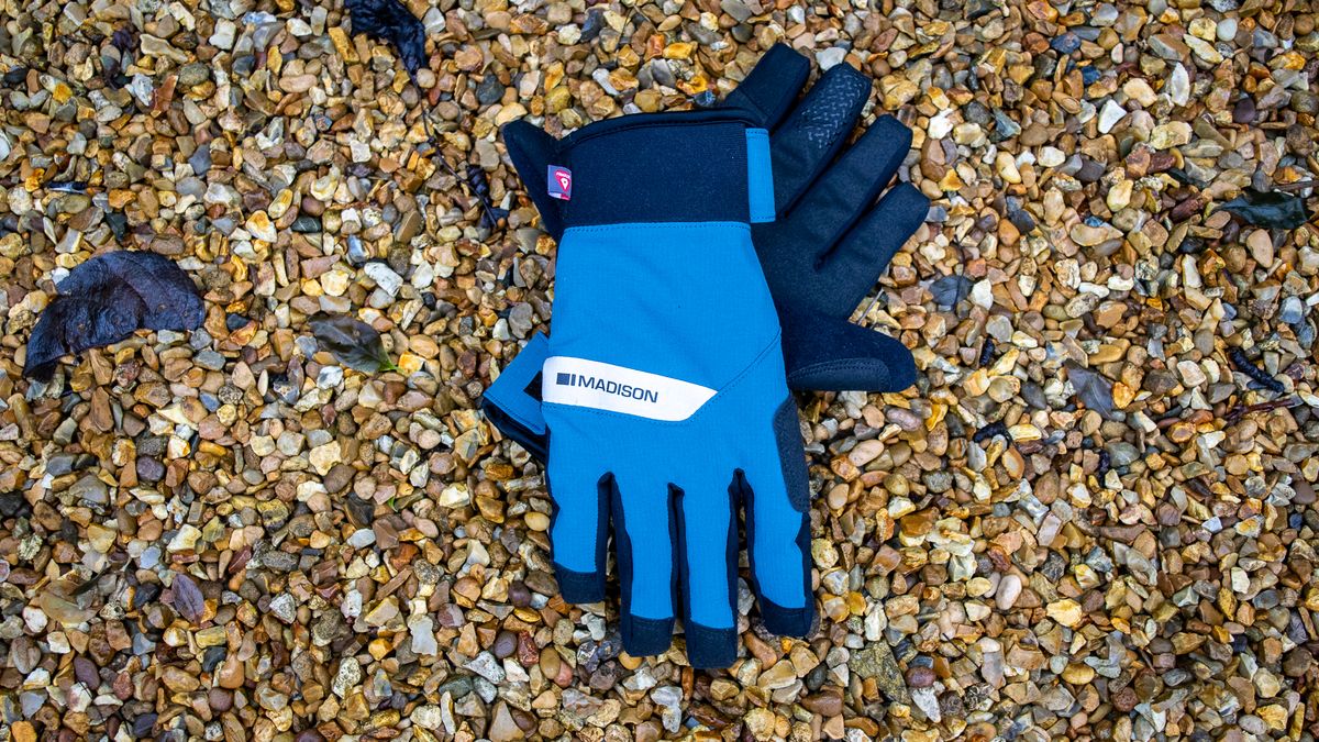 A pair of blue Madison DTE waterproof gloves on gravel