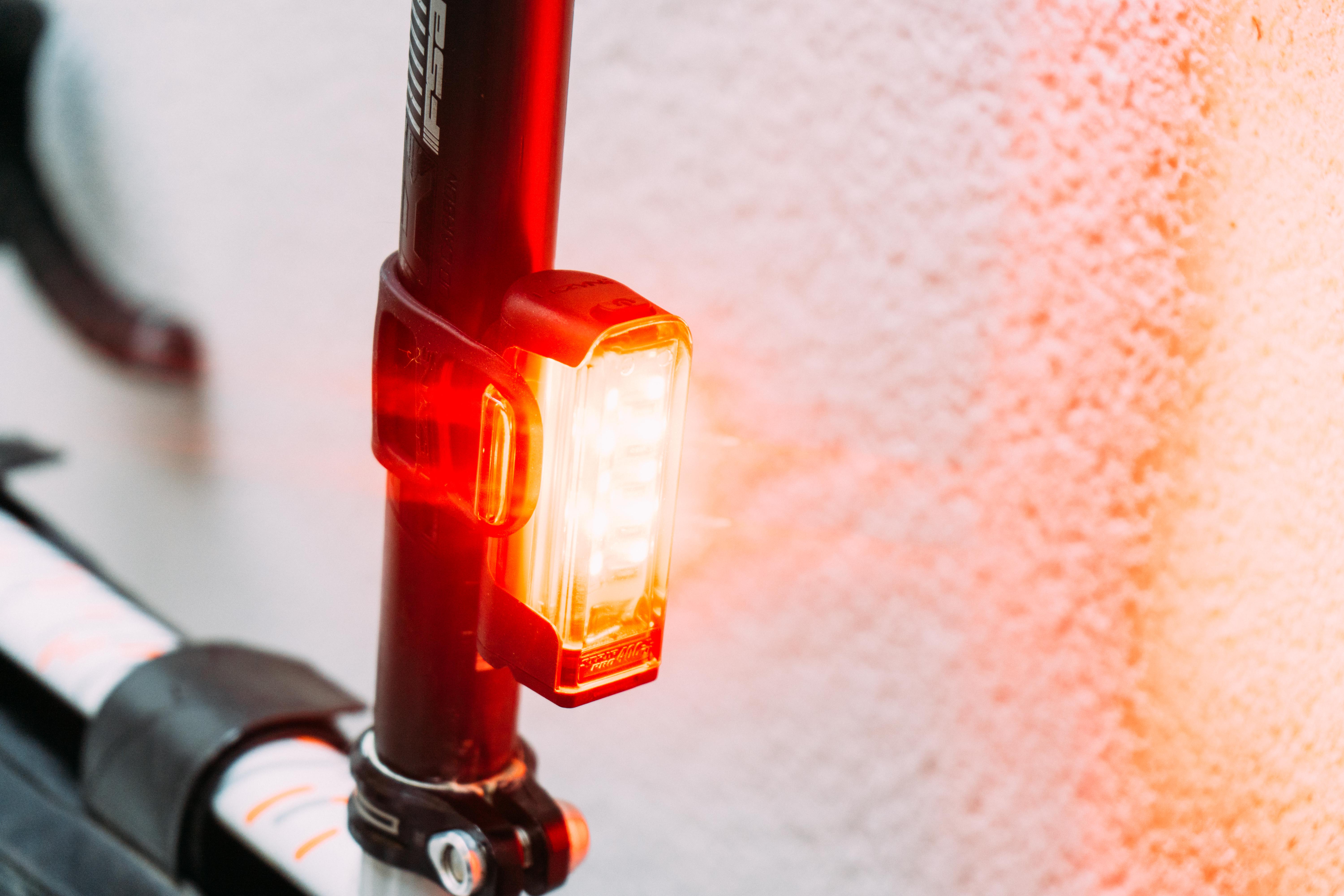 Un feu de vélo rouge fixé à une tige de selle, allumé brillamment