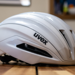 A white Uvex Surge helmet stands on a wooden table