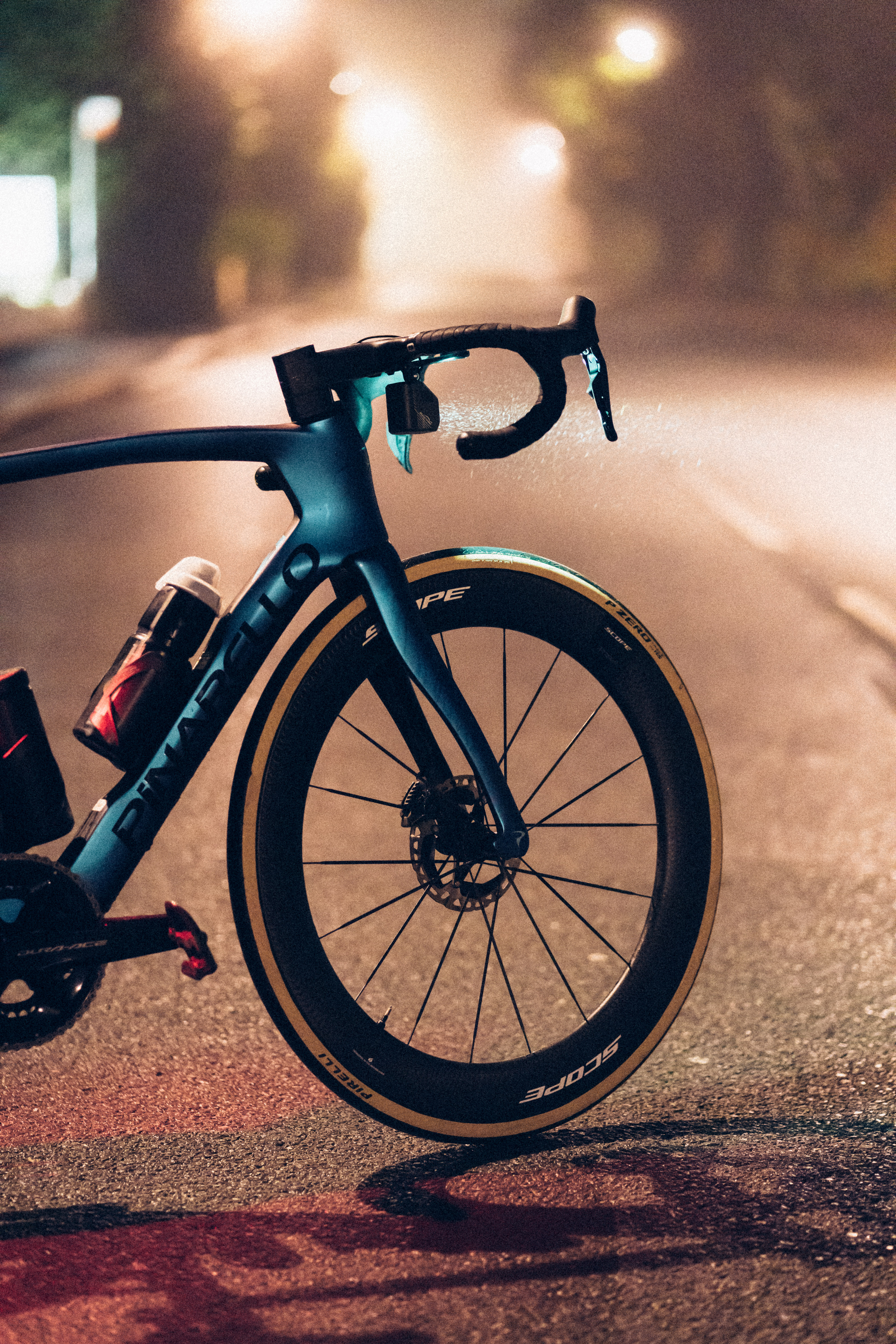 Un gros plan d'un pinarello bleu la nuit dans le brouillard, avec la lumière avant projetant un cône de lumière en avant.